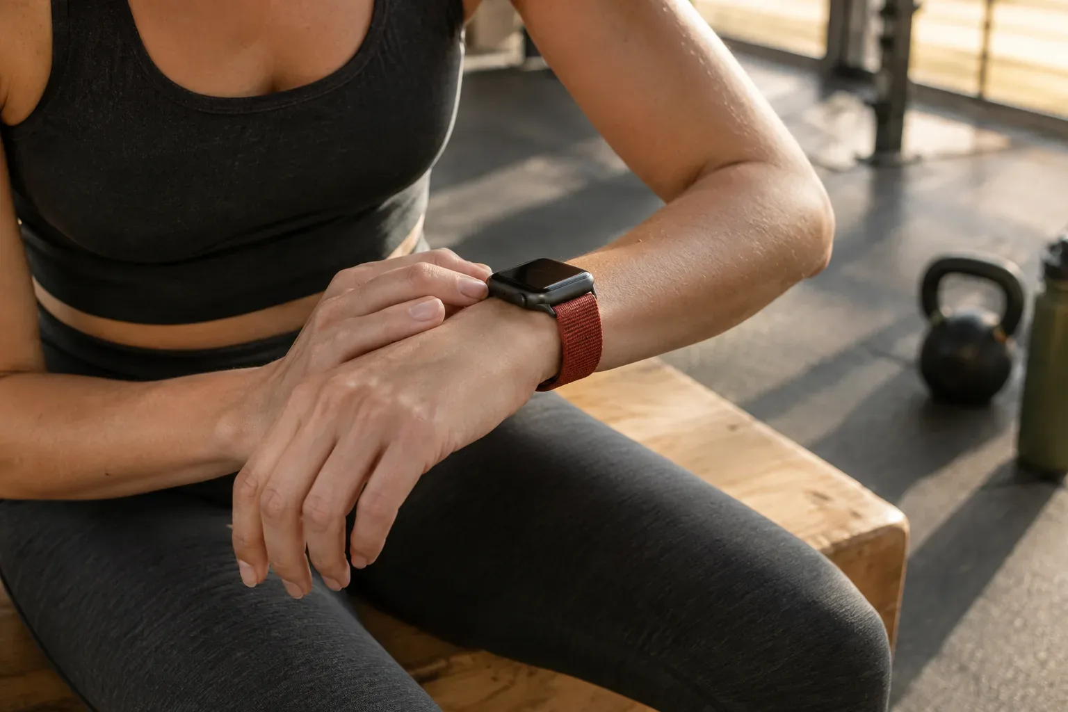 Edzés után a csuklóján viselt, enyhén karcos kijelzőjű Apple Watchot ellenőrzi egy sportoló.